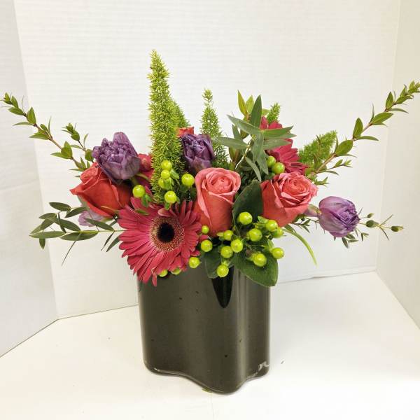 Pink and purple flower arrangement in a dark vase