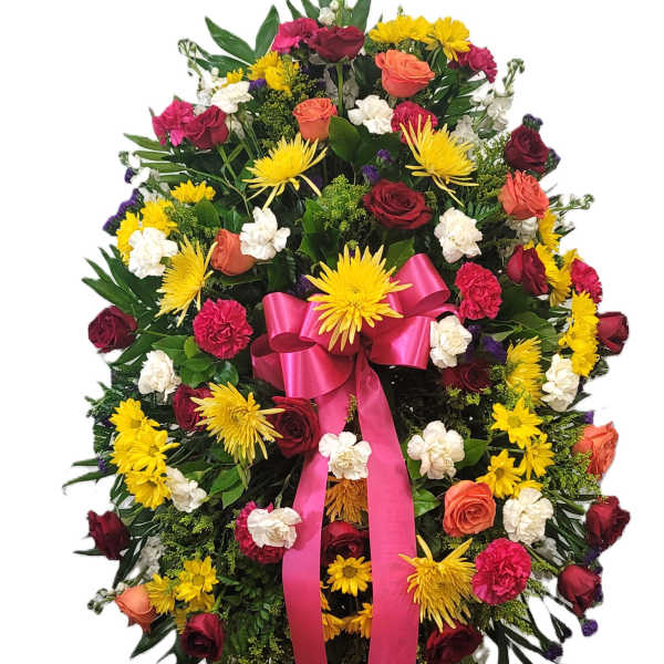 Large standing floral wreath with roses, chrysanthemums, and a pink ribbon