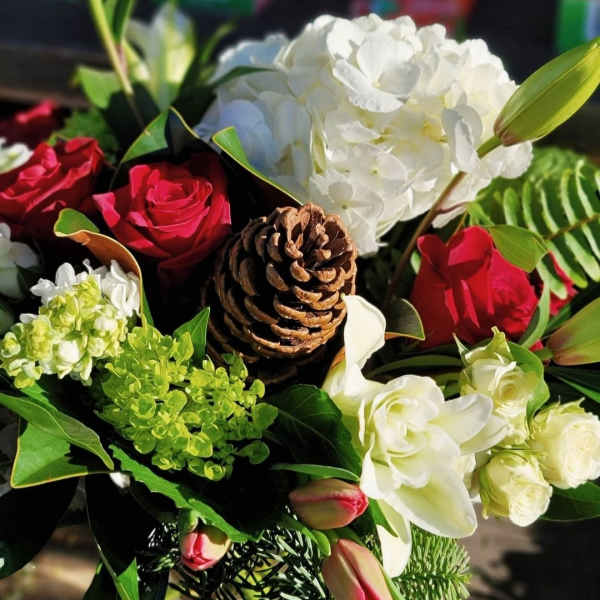 Bouquet of red roses, white hydrangea, and white lilies with a pinecone centerpiece