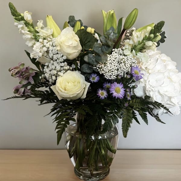 White and lavender floral arrangement in a clear glass vase