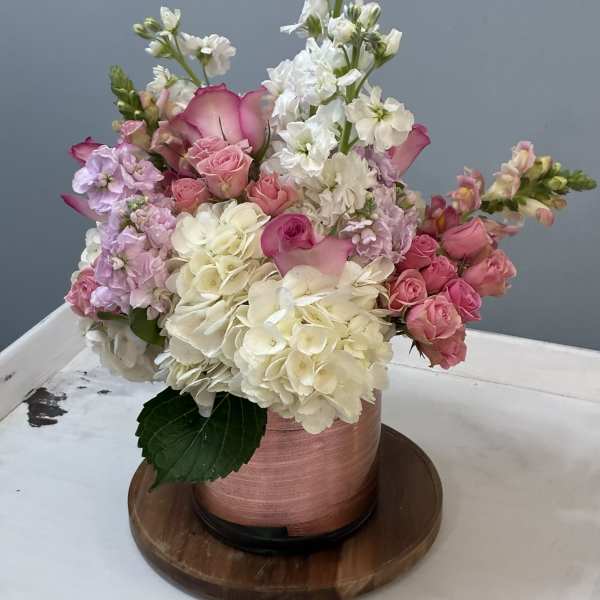 Pink and white floral arrangement in a round hatbox