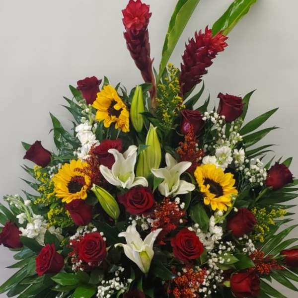 Red roses and white lilies with sunflowers in a vase arrangement