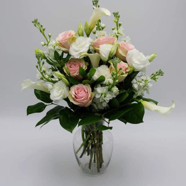 Pink and white roses with calla lilies in a clear glass vase