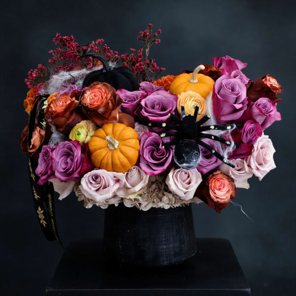 Halloween bouquet of roses with small pumpkins and a spider decoration in a black vase