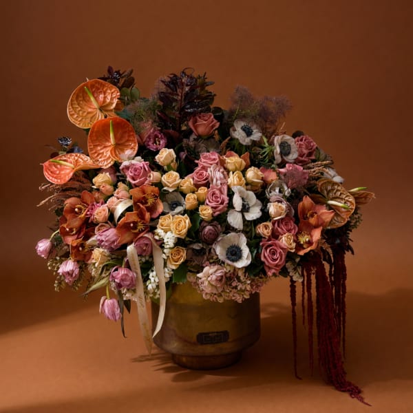 Large mixed bouquet in a gold vase with pink, cream, and orange blooms
