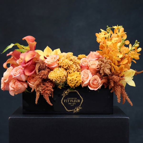 Peach roses, calla lilies, and orange orchids in a black box