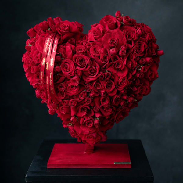 Heart-shaped arrangement of red roses on a red base