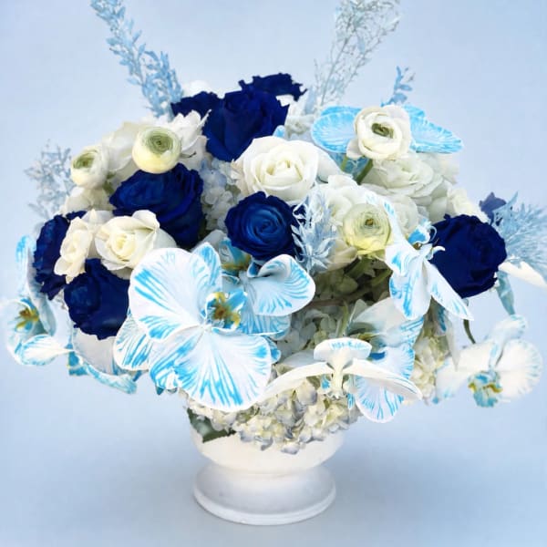 Blue and white floral arrangement in a white pedestal vase