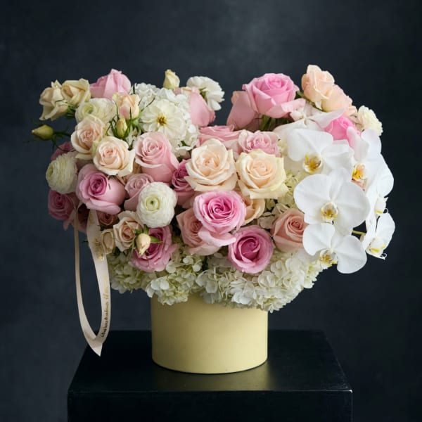 Pink and white roses with orchids in a cream vase