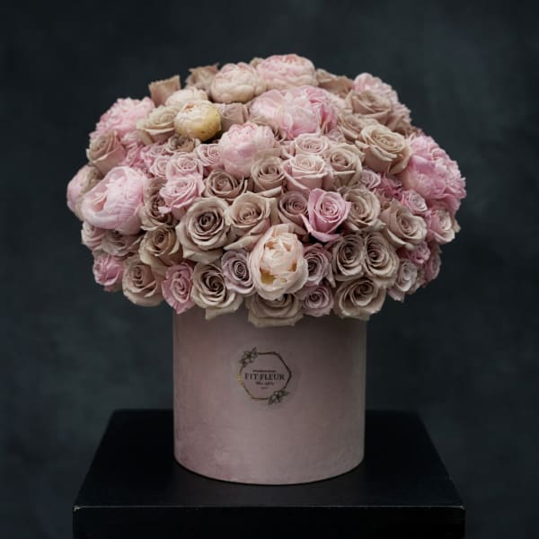 Pink and beige roses arranged in a round box
