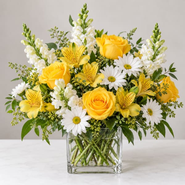 Yellow roses and white daisies in a clear glass vase