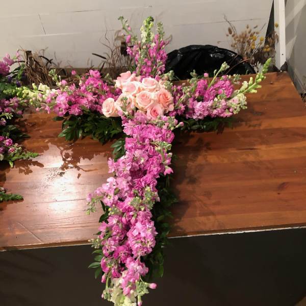 Cross-shaped floral arrangement with pink roses and pink-and-white blooms
