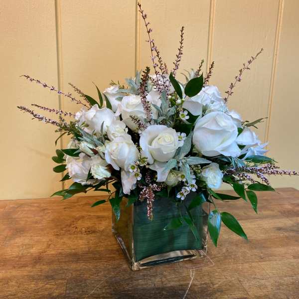 White rose arrangement in a square glass vase with greenery
