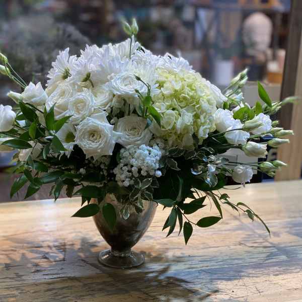 White floral arrangement in a glass vase with greenery