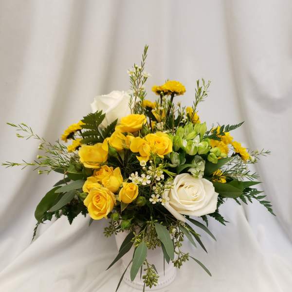 Yellow and white rose arrangement in a white vase