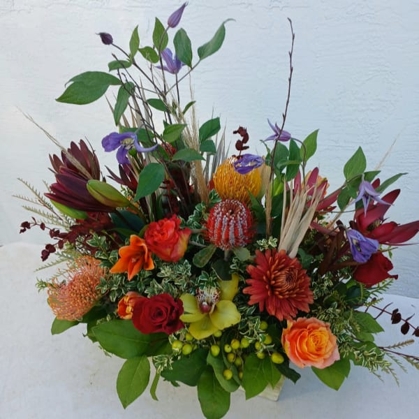 Mixed bouquet with red, orange, yellow, and purple flowers in a low arrangement