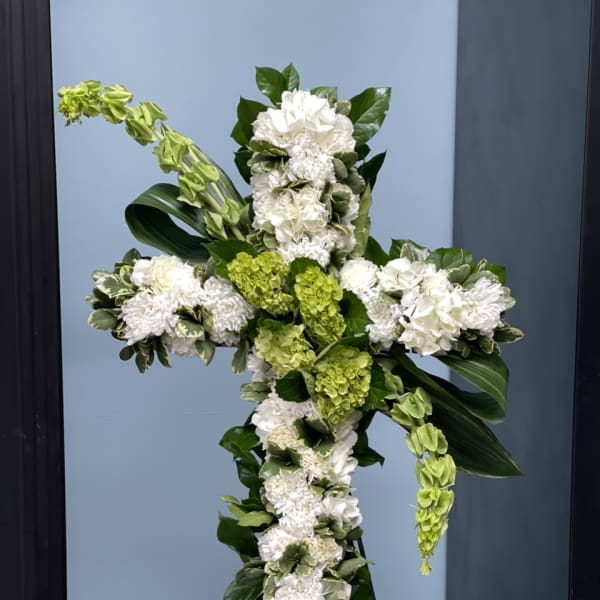 White and green floral cross arrangement on a stand