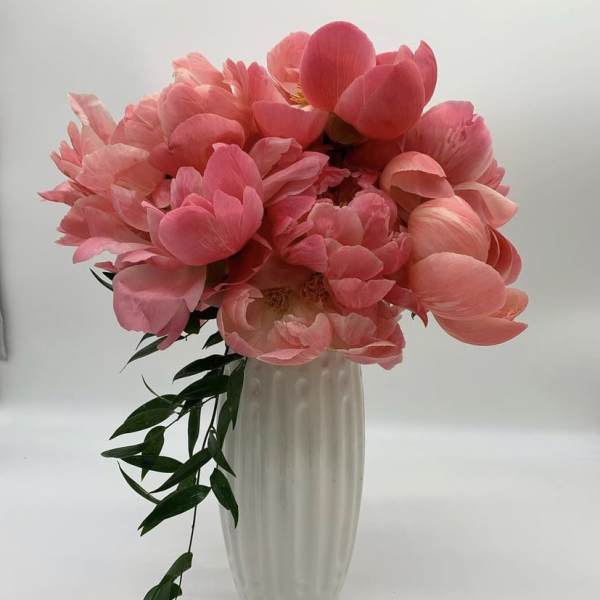 Pink peony bouquet in a tall white vase