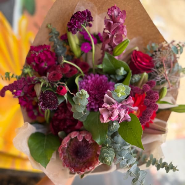 Bouquet of magenta and red flowers wrapped in brown paper