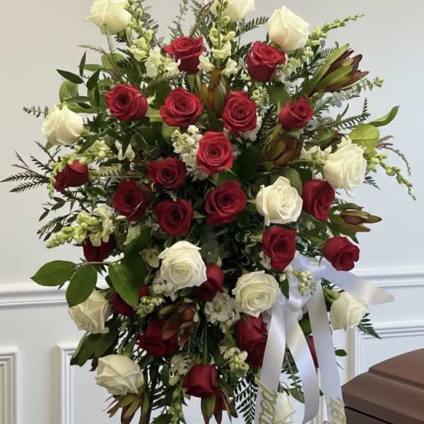 Standing spray of red and white roses with ribbon on an easel