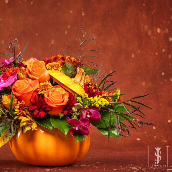 Orange and magenta floral arrangement in a pumpkin-shaped vase