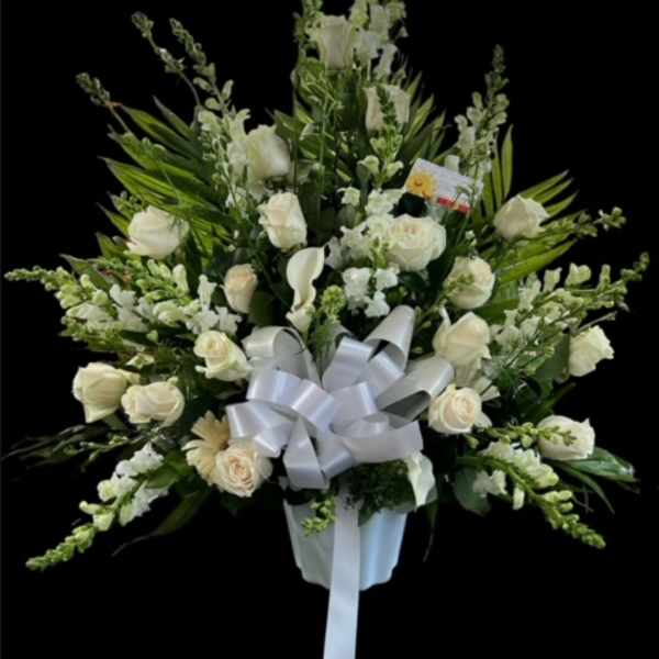 White rose and calla lily arrangement with a silver bow in a white vase