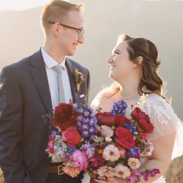 Bride and groom holding a colorful wedding bouquet and boutonniere