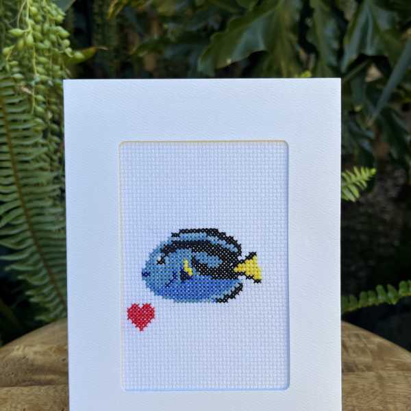 White greeting card with a small cross-stitch fish and red heart