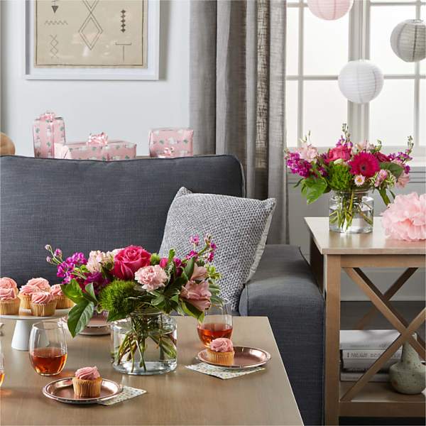 Pink and magenta flower arrangements in glass vases on a living room table