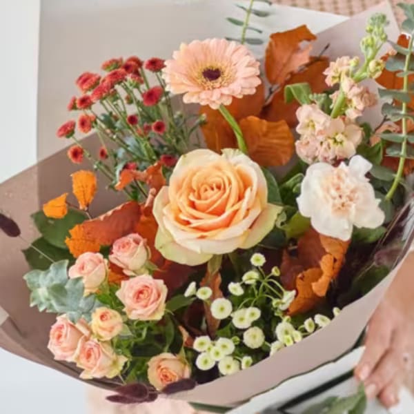 Bouquet of peach and pink flowers wrapped in paper