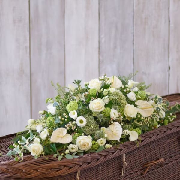 White floral casket spray with roses, calla lilies, and green accents