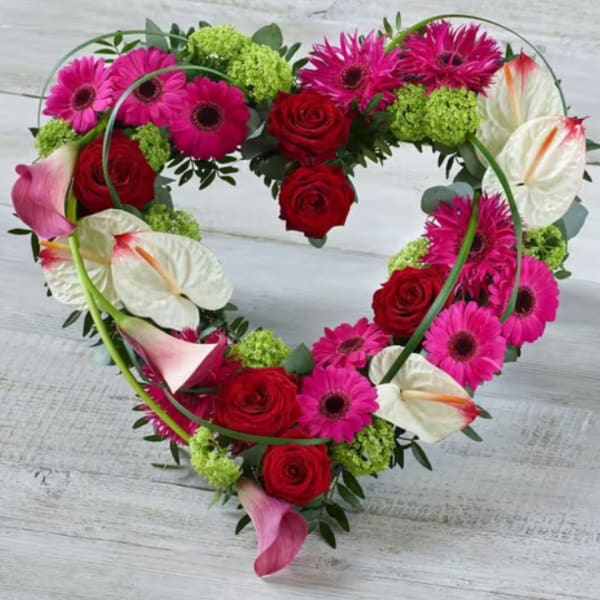 Heart-shaped floral arrangement with red roses, pink gerberas, and white calla lilies
