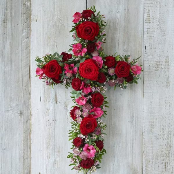 Cross-shaped floral arrangement with red roses and pink blooms