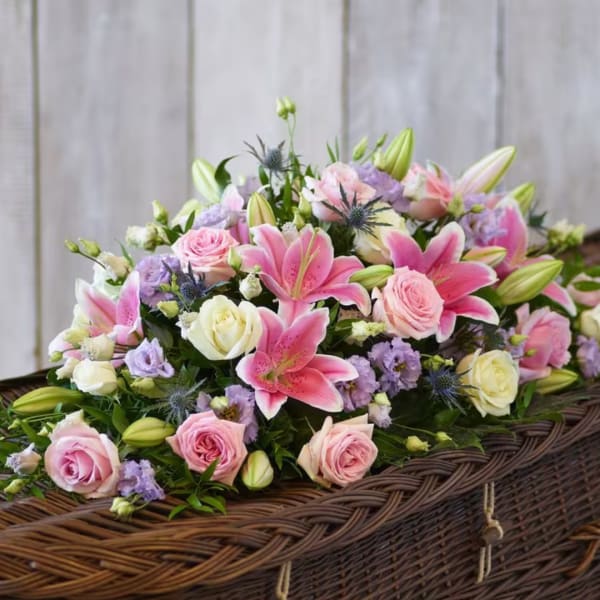 Pink lilies and roses arranged in a wicker basket
