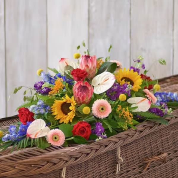 Colorful floral casket spray with sunflowers, roses, and anthuriums