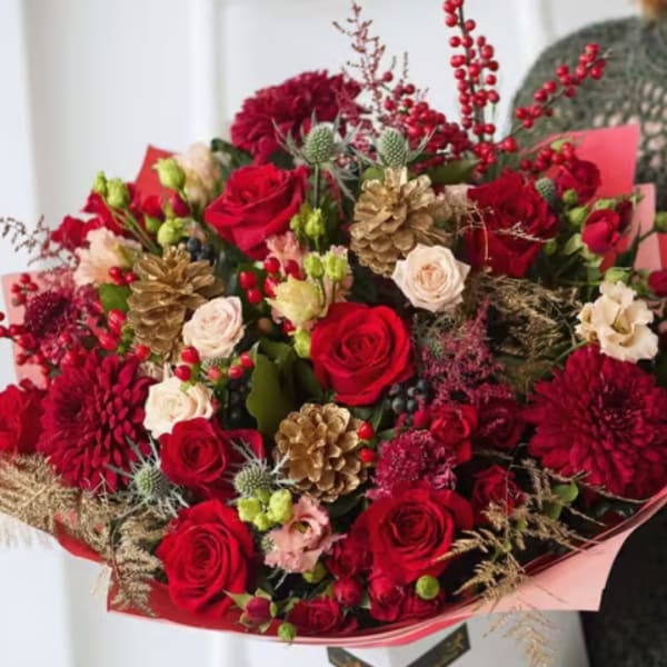 Bouquet of red roses and burgundy blooms with gold pinecones