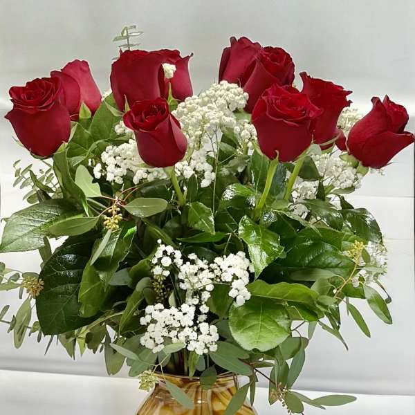 Red roses arranged in a marbled glass vase with white filler flowers