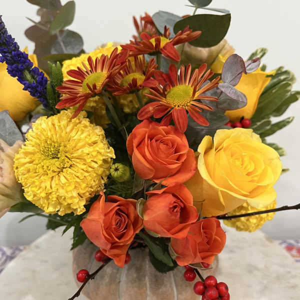 Bouquet of yellow and orange roses with chrysanthemums in a pumpkin vase