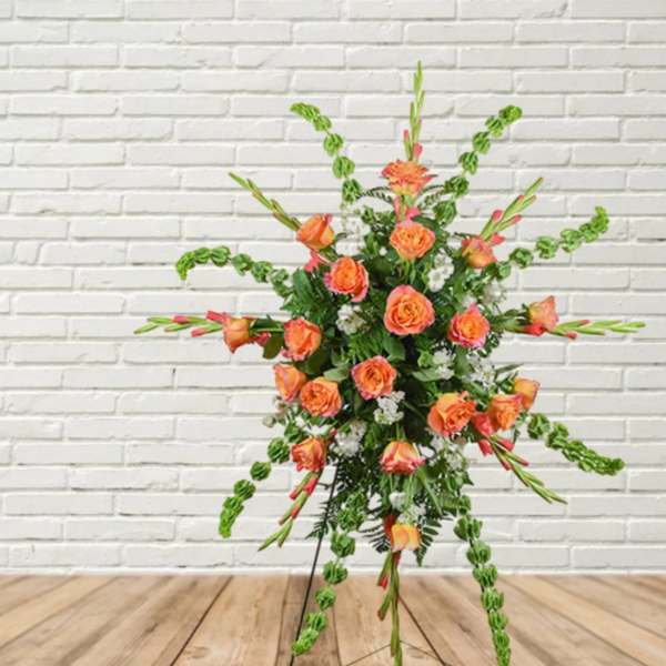 Orange roses in a tall standing floral spray with green accents