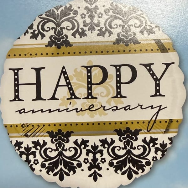 Decorative "Happy anniversary" sign with black floral patterns on a blue background
