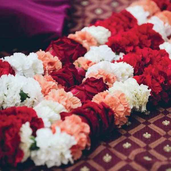 Rows of red, white, and peach flower garlands laid on patterned fabric