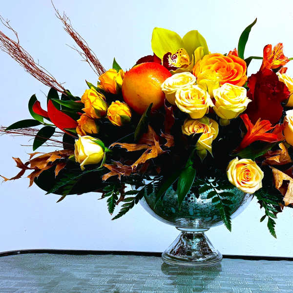 Bouquet of yellow and orange roses in a glass vase with autumn leaves