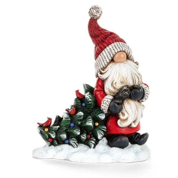 Santa figurine beside a small decorated Christmas tree on a snowy base