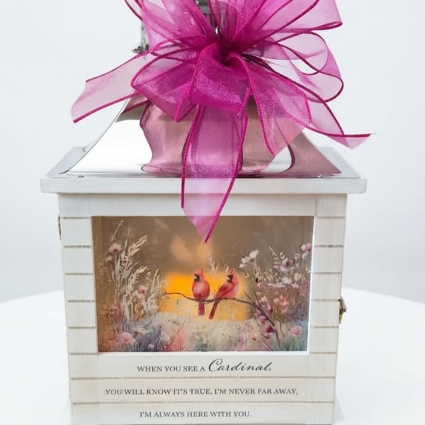Decorative white lantern with a large pink bow and cardinal artwork