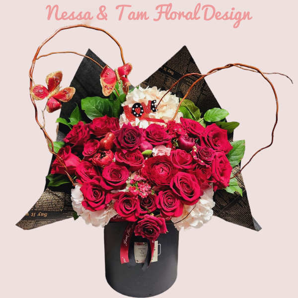 Bouquet of red roses and white hydrangeas in a black box with butterfly accents