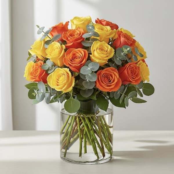Bouquet of yellow and orange roses in a clear glass vase