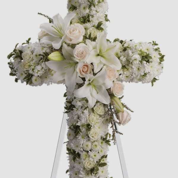 White floral cross arrangement with lilies and roses on an easel