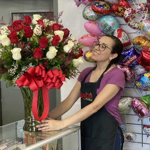 Tall bouquet of red and white roses in a glass vase with a red bow