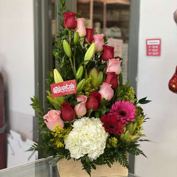 Tall bouquet of pink and red roses with white hydrangea in a wooden box