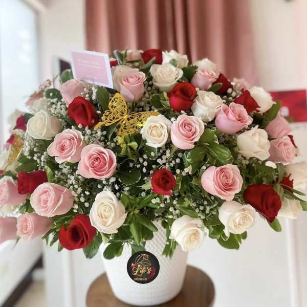 Large bouquet of pink, red, and white roses in a white vase